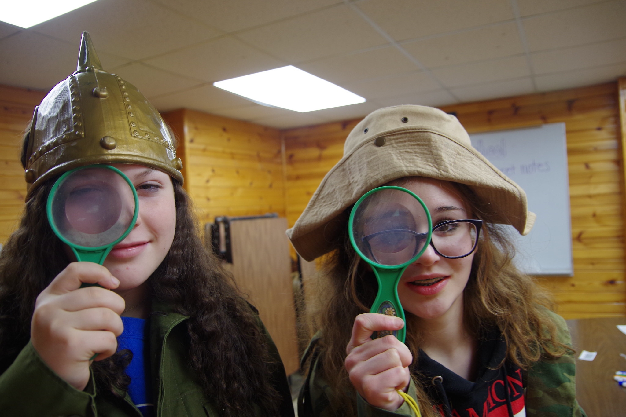 Two campers in costumes hold up magnifying glasses to their eyes.