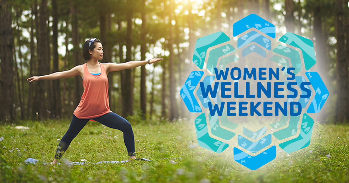 A woman strikes a yoga pose in a field surrounded by trees