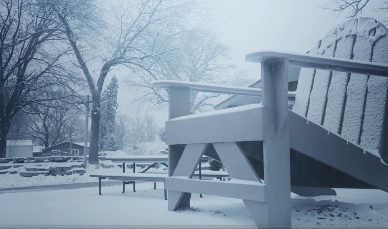 A Giant Adirondak Chair sits in the foreground of a snow covered scene.