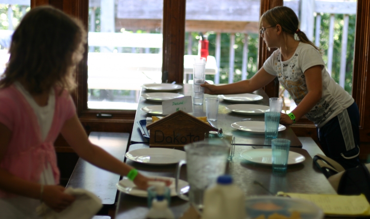 Two campers set the table for lunch in the dining hall