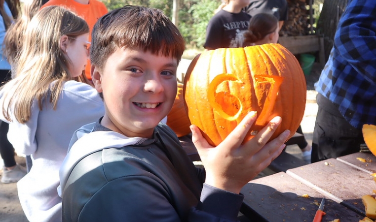A kid shows off the pumpkin they carved with Six Seven