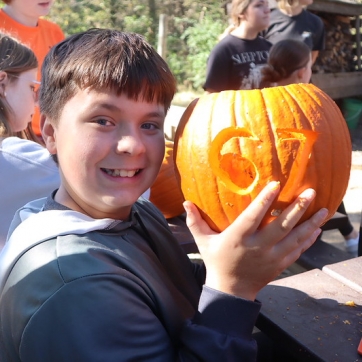 A kid shows off the pumpkin they carved with Six Seven