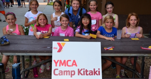A cabin group poses with their counselor on a picnic table