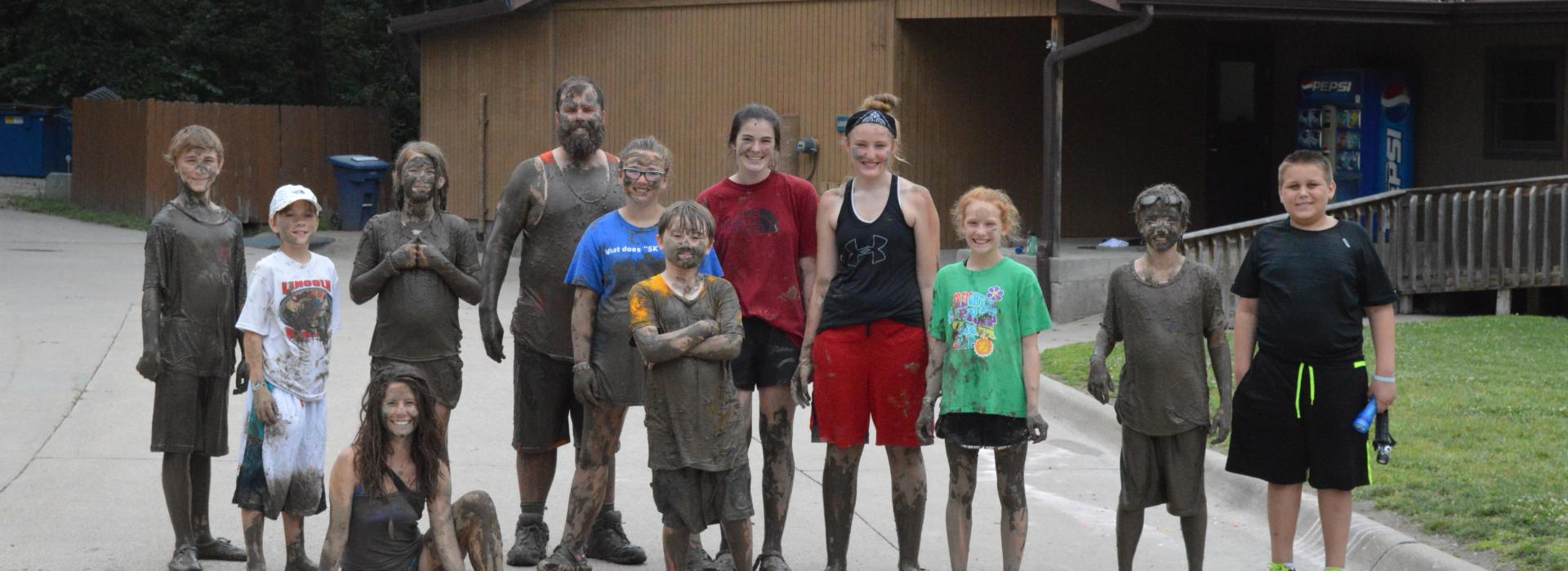 A group of campers in staff covered in mud after a mud hike