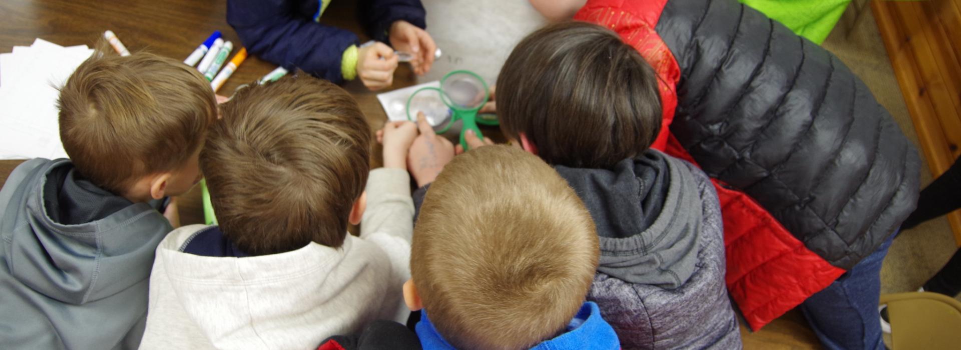 Campers gather around paper as they get finger printed