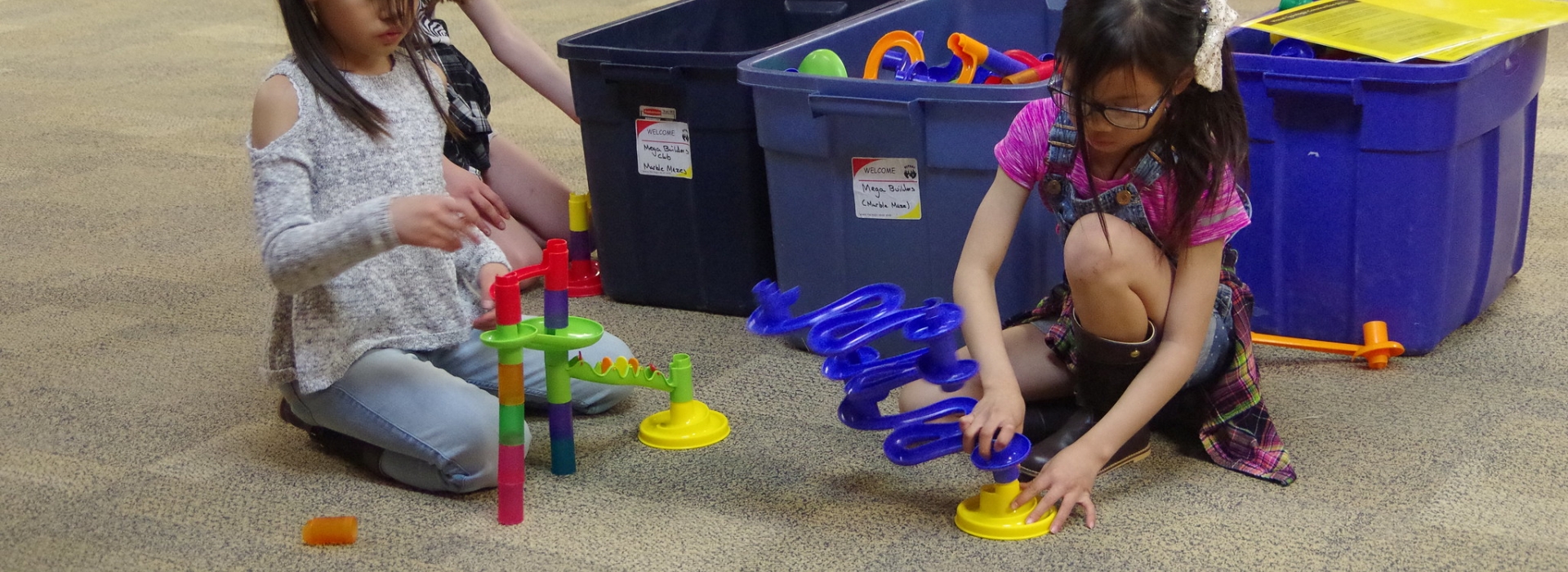 Two campers work together on building a marble maze construction