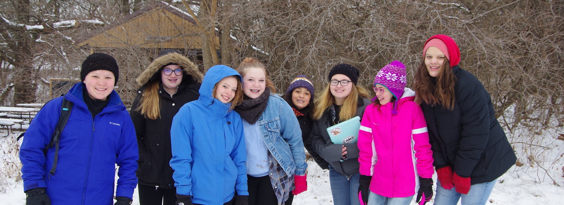 8 campers in winter gear smile in the snow