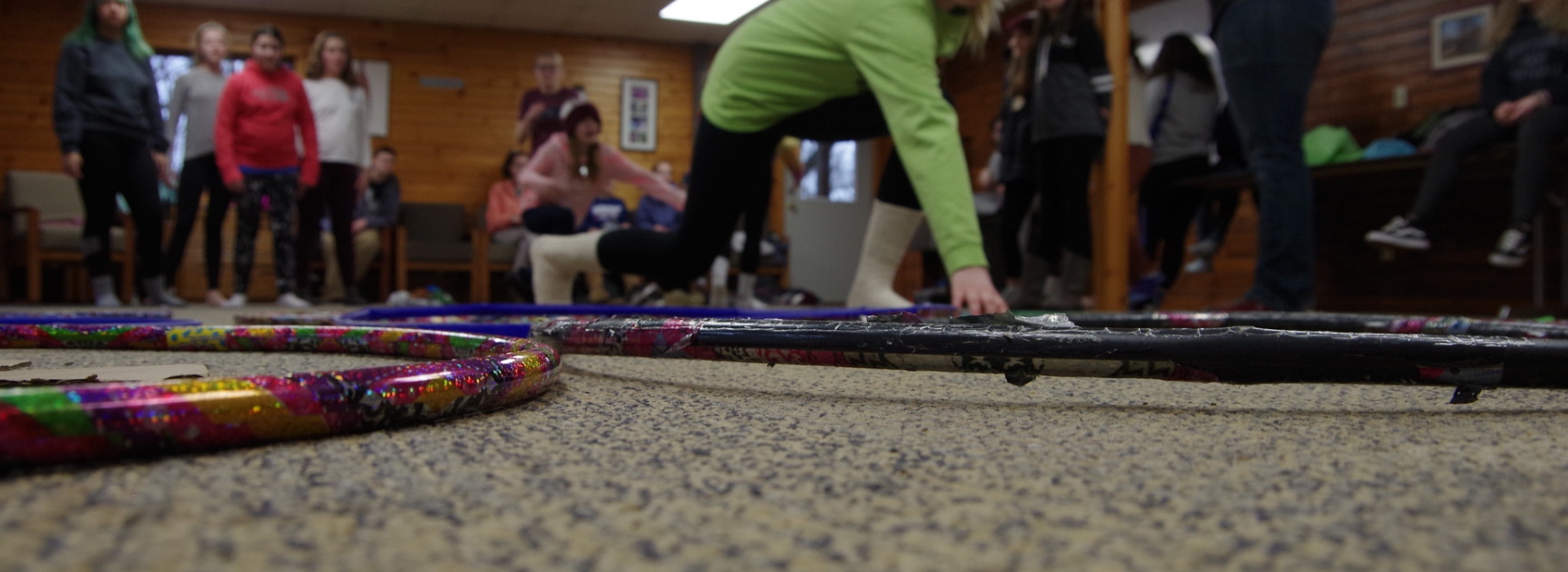 A camper places an object in a hula hoop during a relay