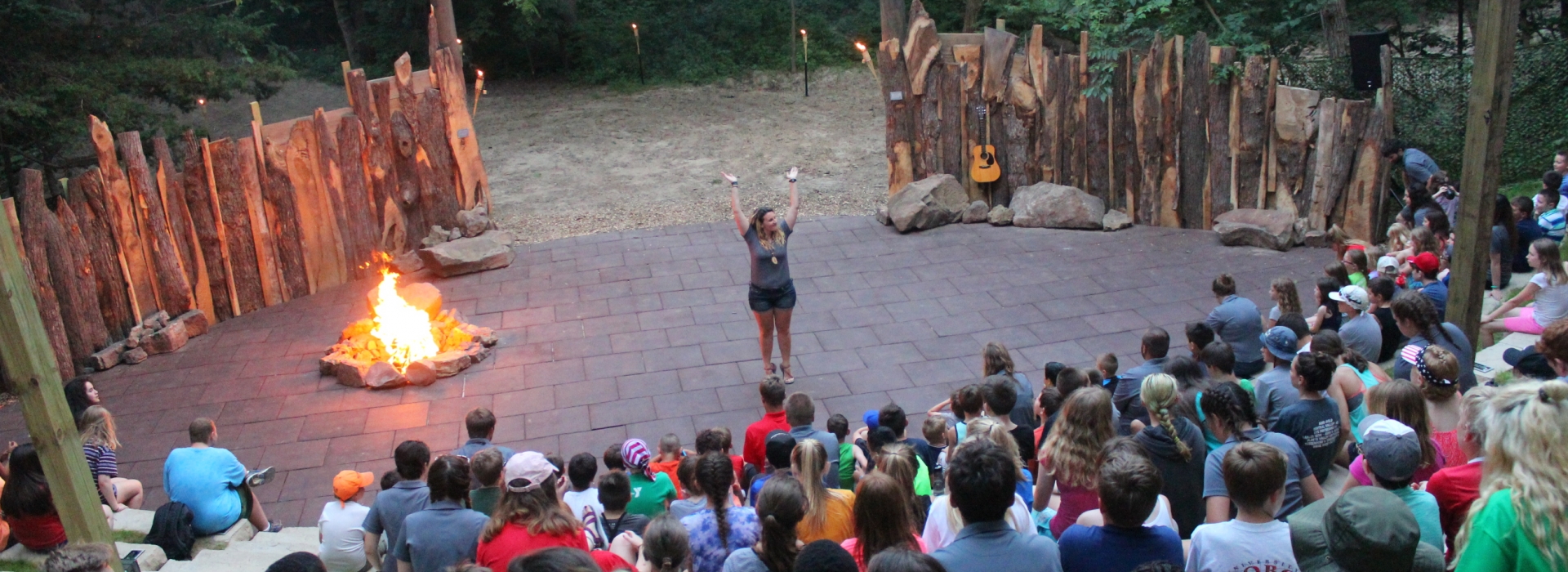 A staff member stands on stage to lead a song at our campfire amphitheater