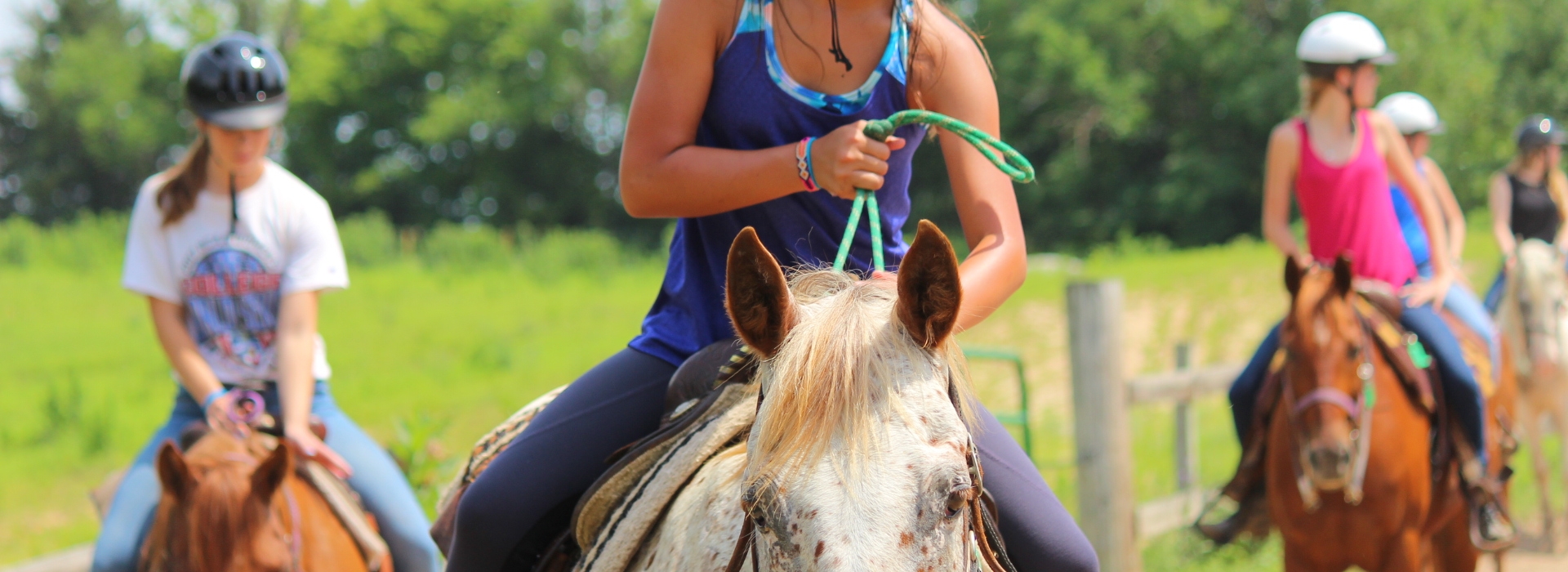A camper talks to her horse as she rides in the arena