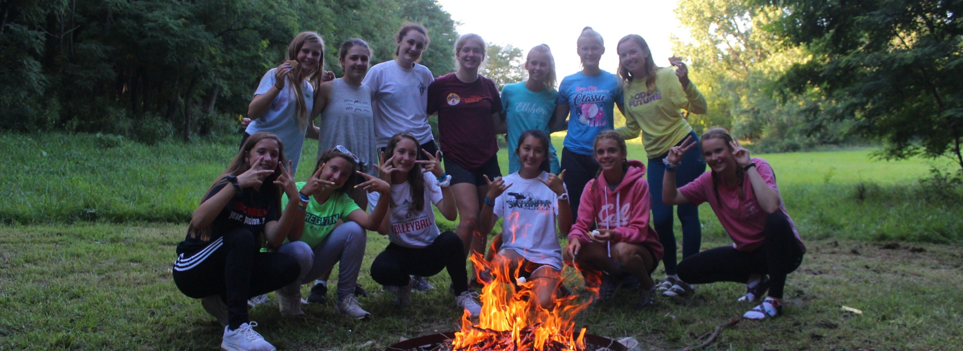 A cabin of trailblazers campers pose behind a fire pit