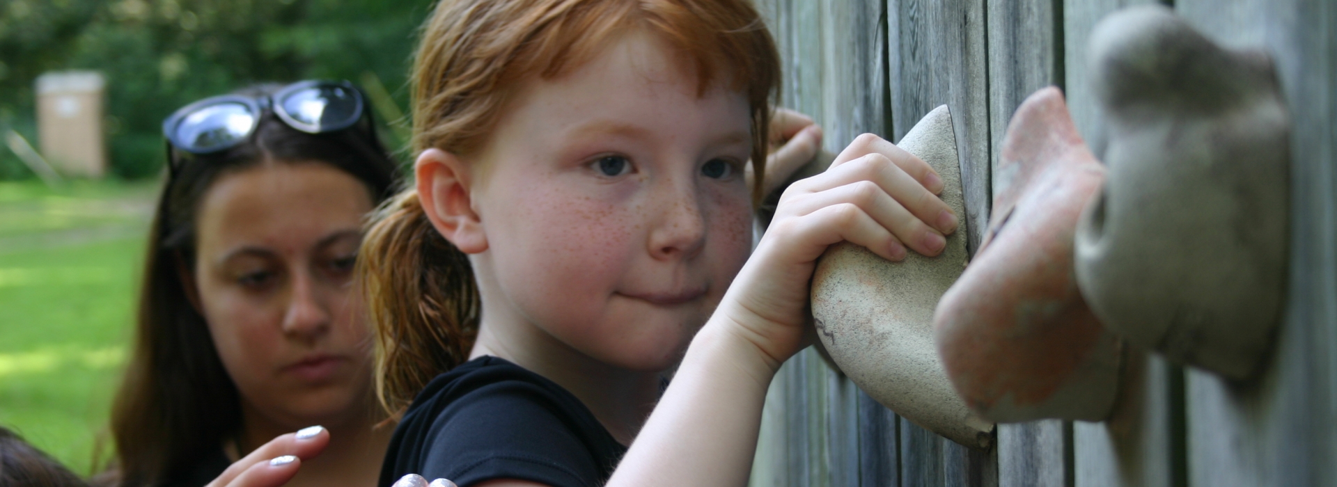 A camper climbs the bouldering wall while staff spot
