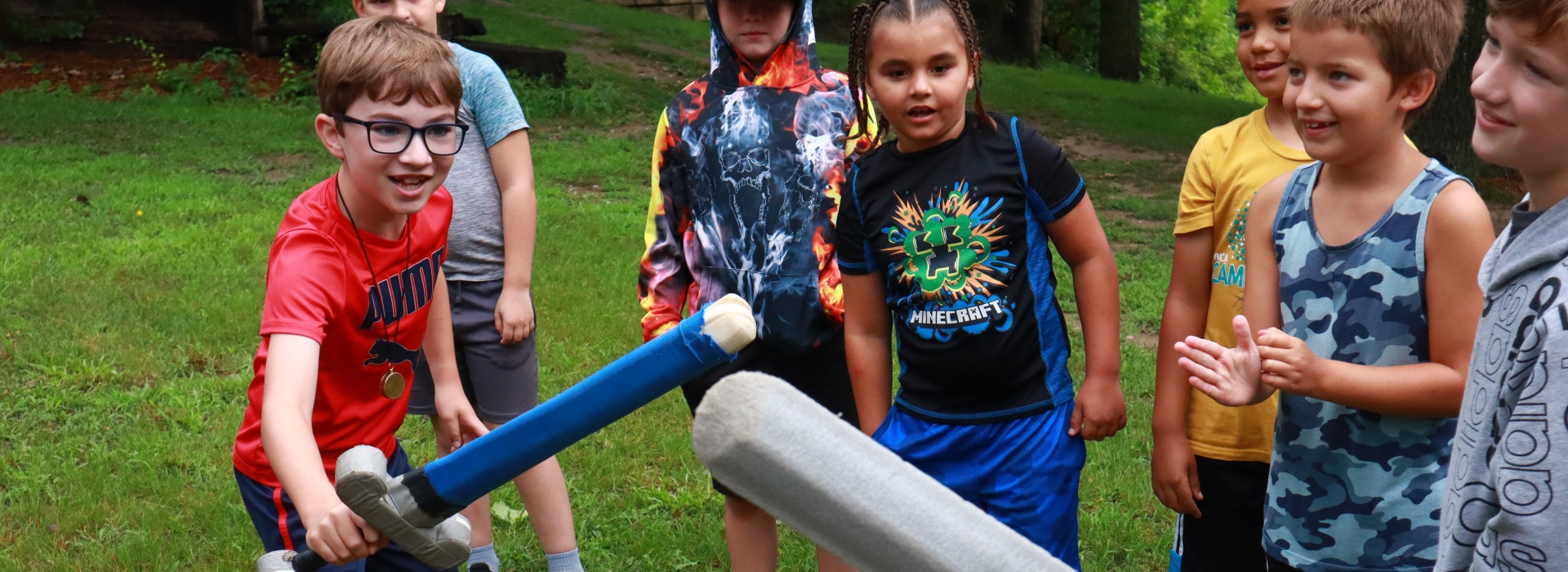 group of campers sword fighting with foam swords with peers cheering on in background