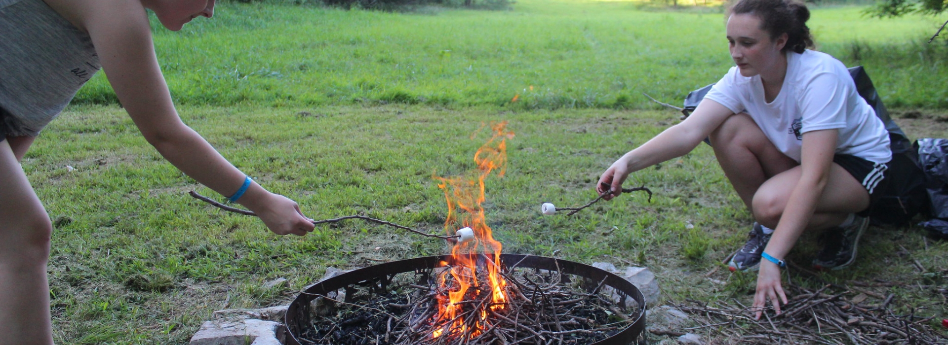 Two people roast marshmellows over a fire