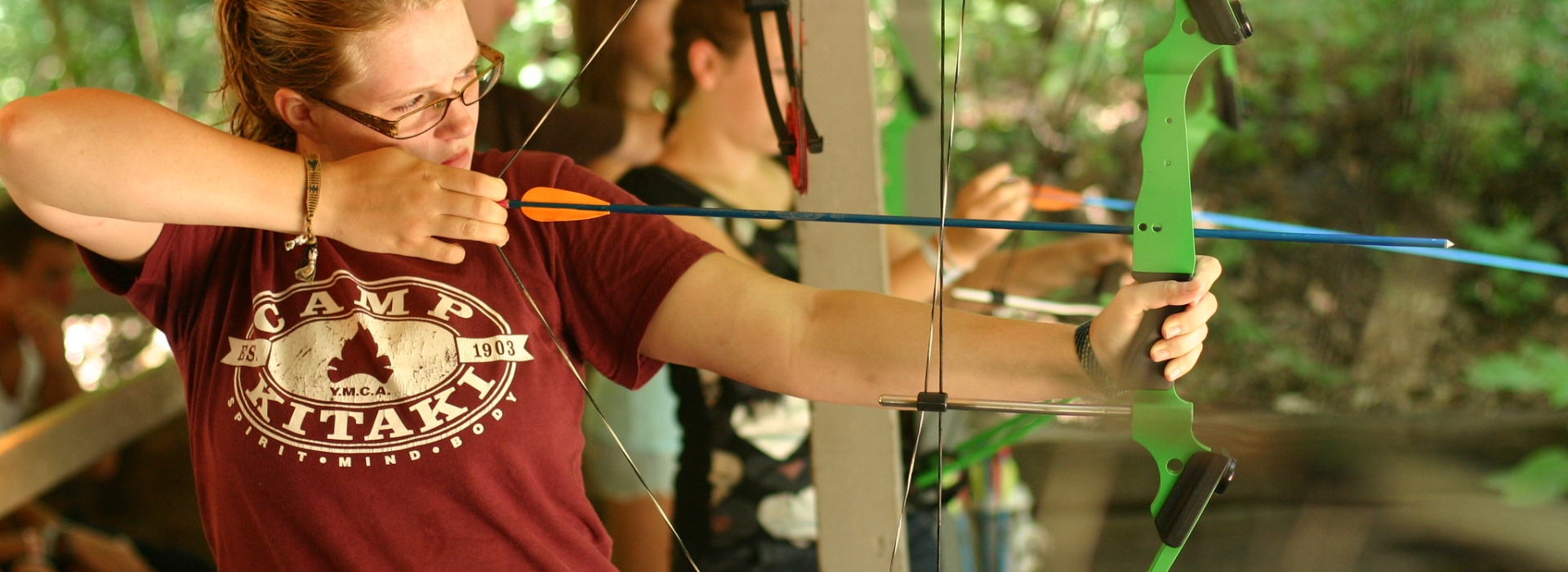 A person looks down an arrow aiming the bow